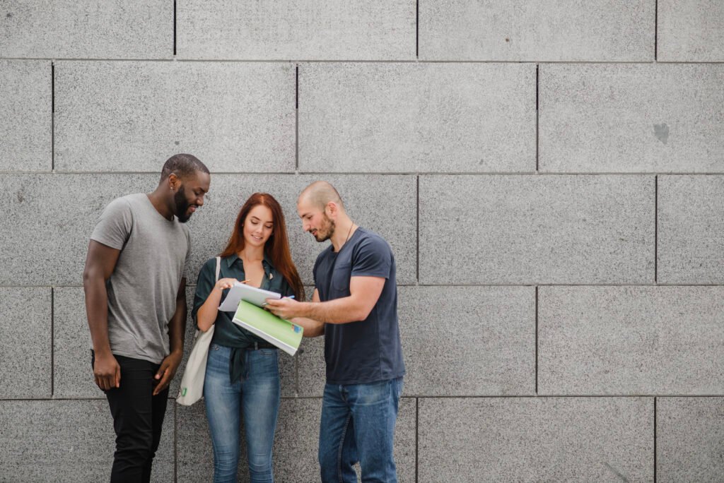 students holding notebooks standing smiling